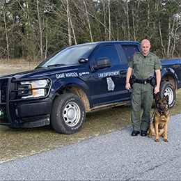 Game Warden and K-9 in front of his law enforcement truck