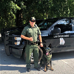 Game Warden and K-9 in front of his law enforcement truck